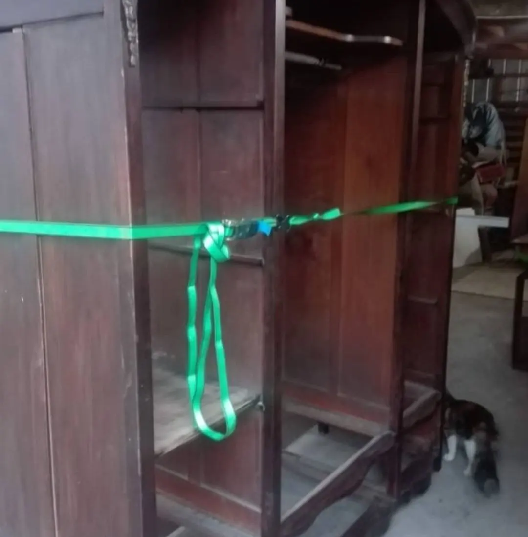 Ropero antiguo de madera, amarrado con cintas al llegar al taller